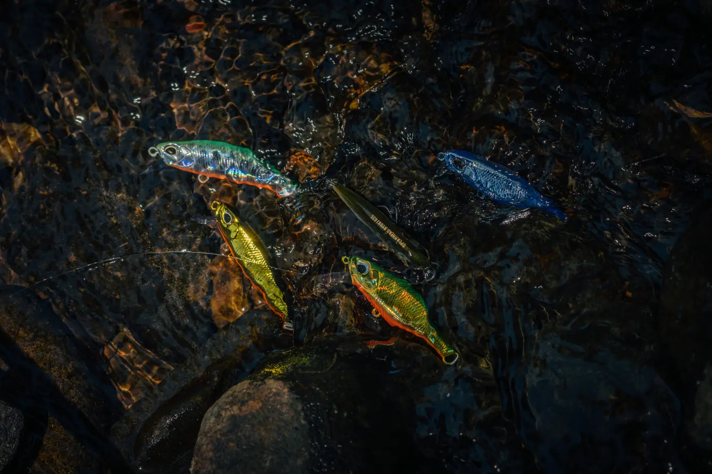 Várias iscas coloridas sobre pedras no rio
